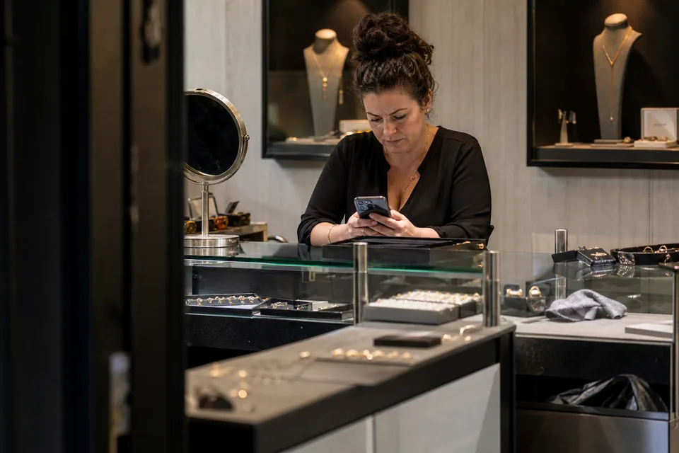 Sales associate in a boutique reading the day's client list on her phone