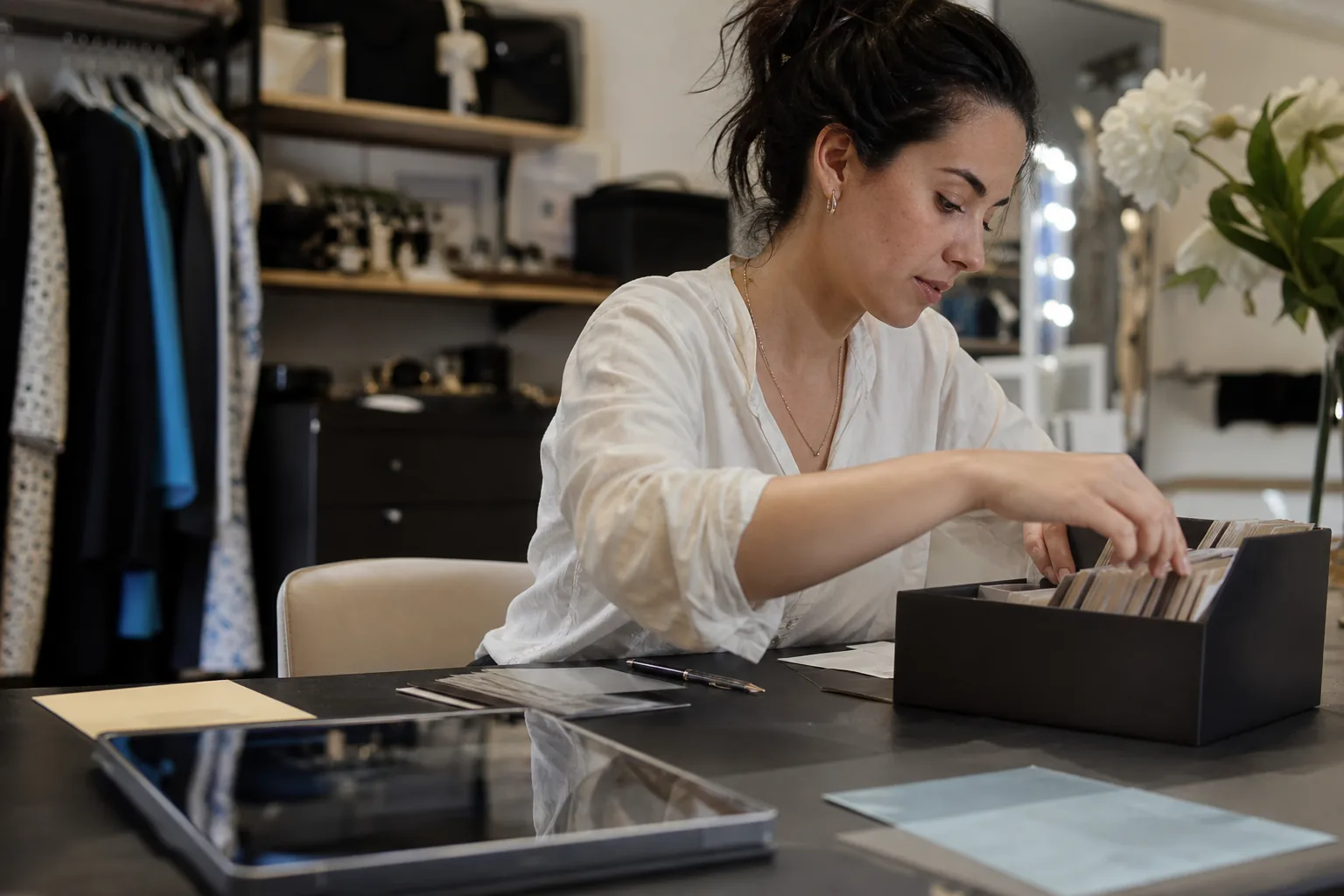 Watch boutique associate reviewing client records on a tablet behind a display counter