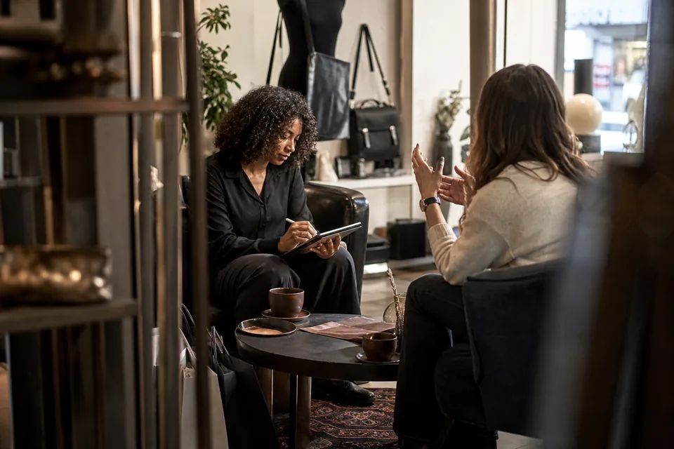Retail associate updating a customer profile on a tablet during a consultation with a client