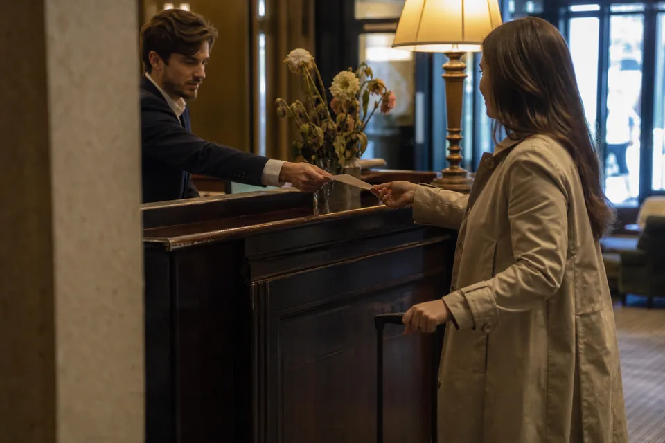 Hotel concierge greeting a returning guest by name at the front desk of a luxury hotel lobby