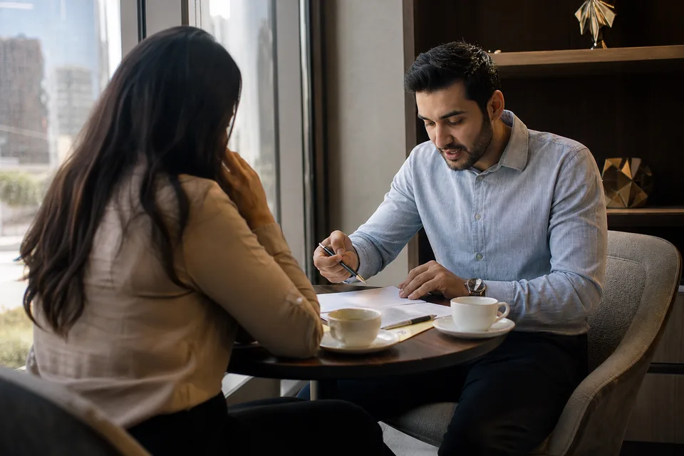 Relationship manager meeting a private banking client in a quiet office with a city view