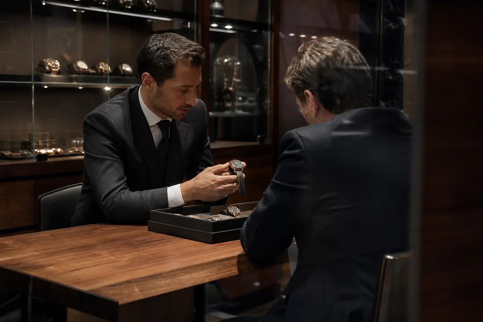 Watch boutique at evening with a client trying a watch at the counter